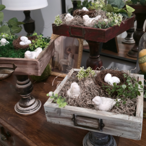 Handcrafted rustic wood drawer pedestal stands with white distressed and dark stained finishes holding spring bird nests.